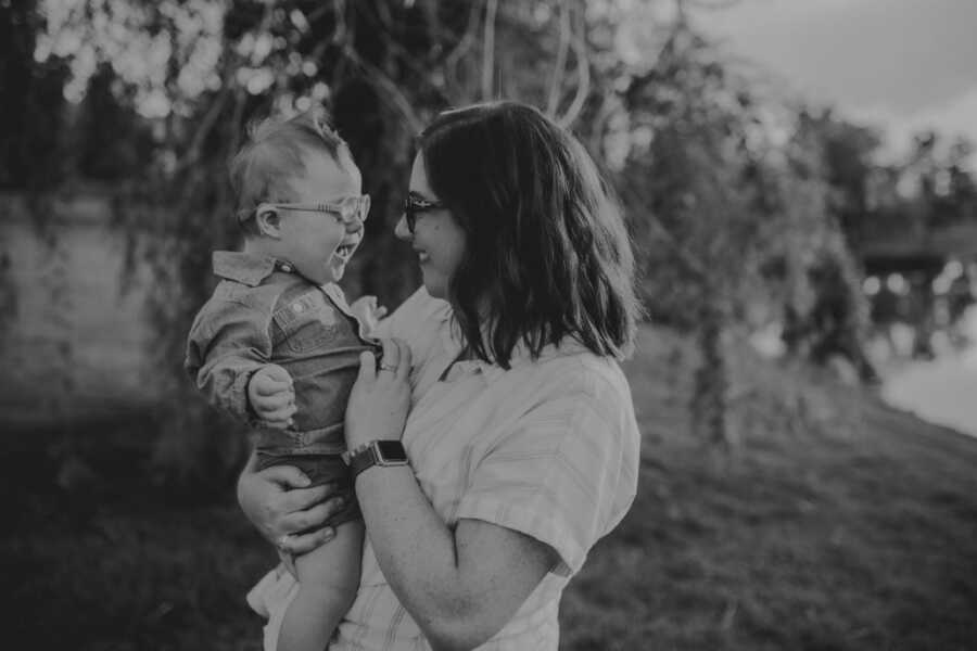 Mom smiles at her son with Down syndrome while taking family photos