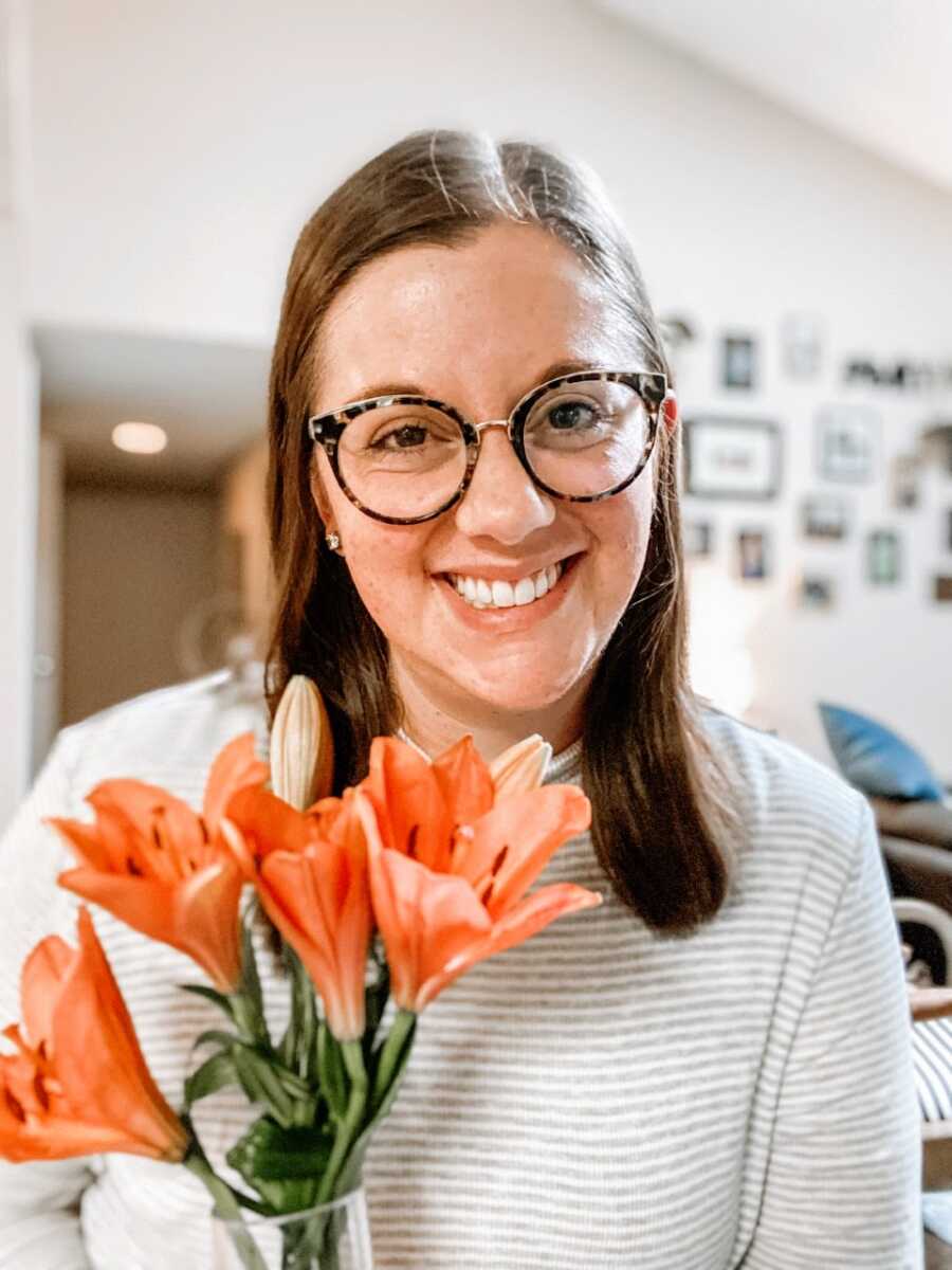 Mom of two sons smiles for a photo with orange flowers