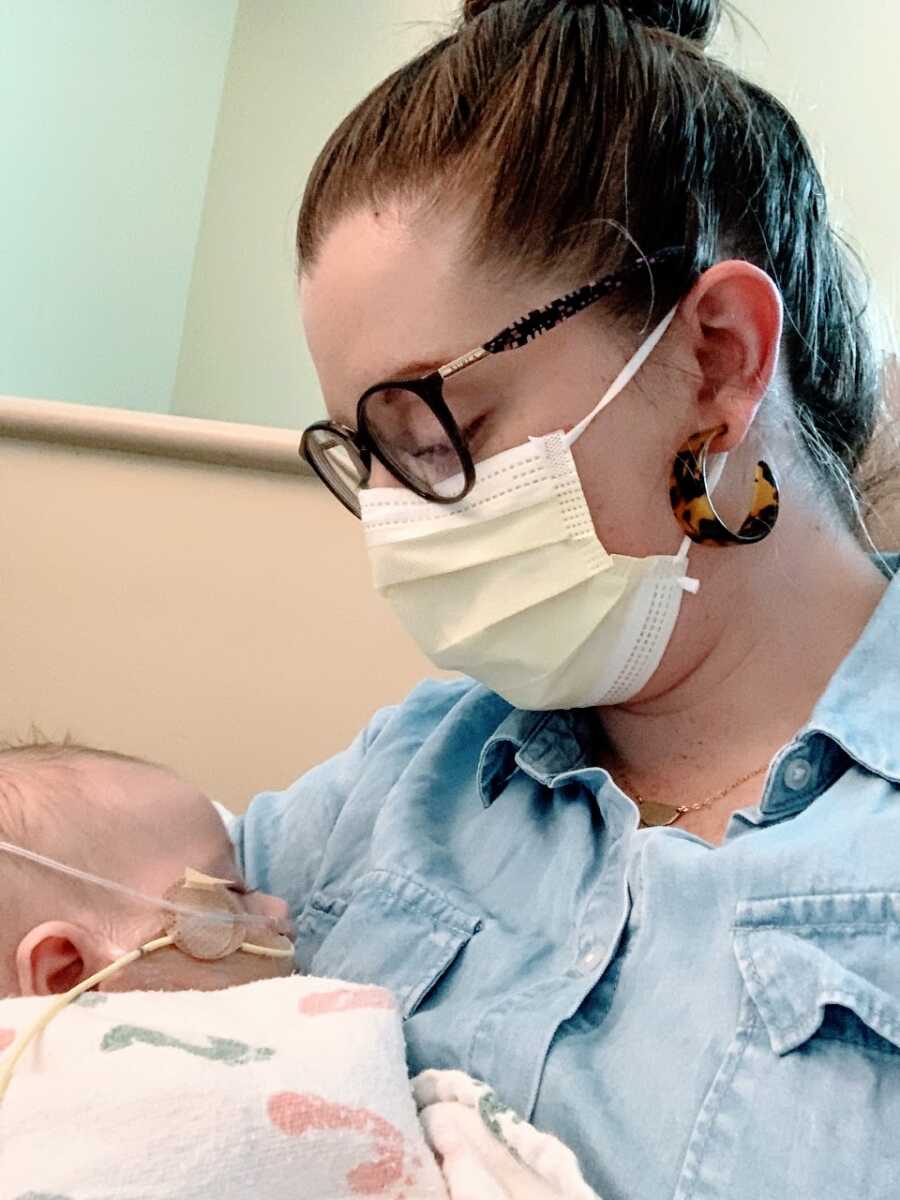Mom looks down at newborn son with health complications while holding him in the hospital