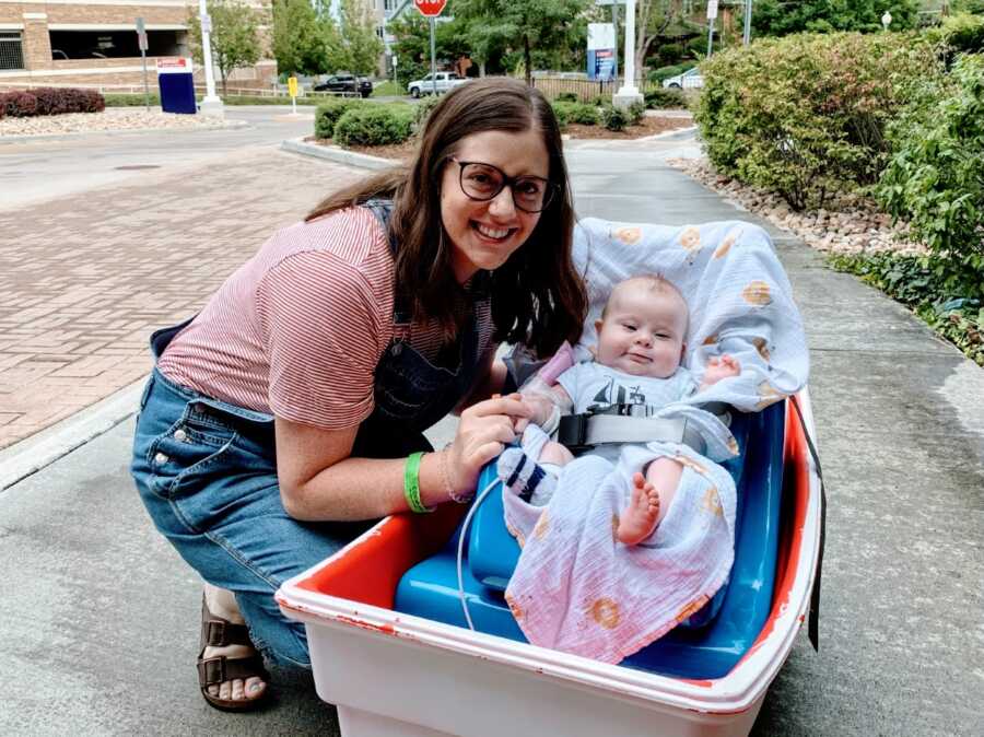 Mom crouches down next to her son with Down syndrome in a wagon