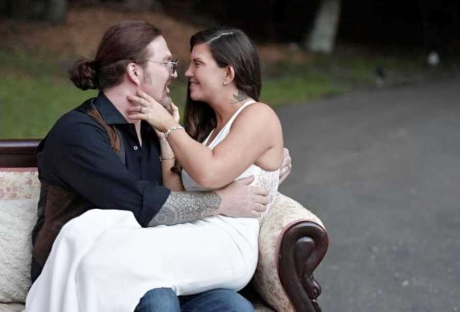 Newlywed couple take intimate photo sitting on an antique couch