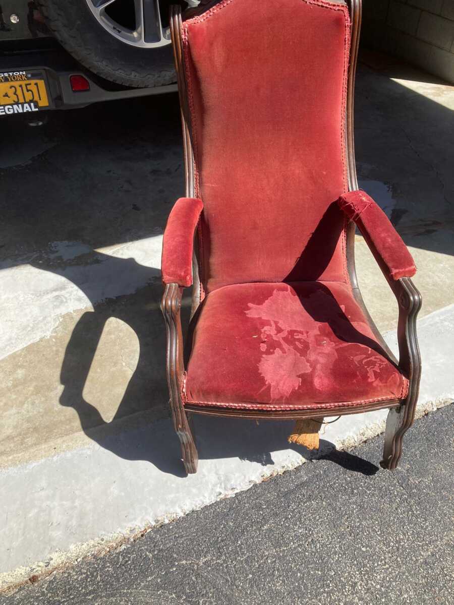 Woman takes a photo of her antique claw-footed red chair from her grandmother