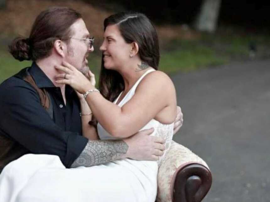Newlyweds take an intimate photo with each other on an antique couch during their wedding photoshoot