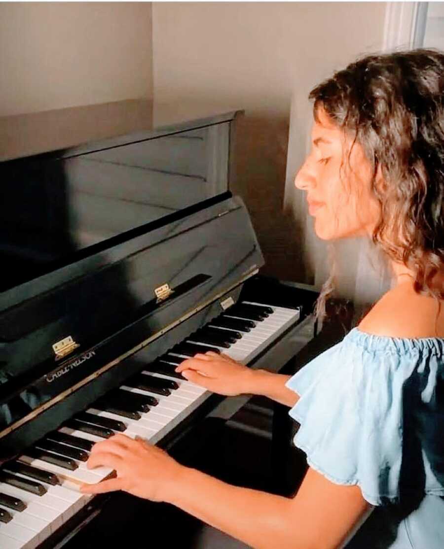 Woman in blue off the shoulder shirt focuses on playing the piano