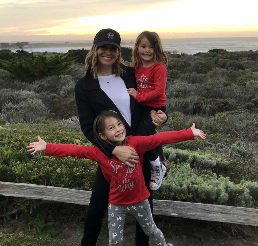 mom and two daughters posing outside