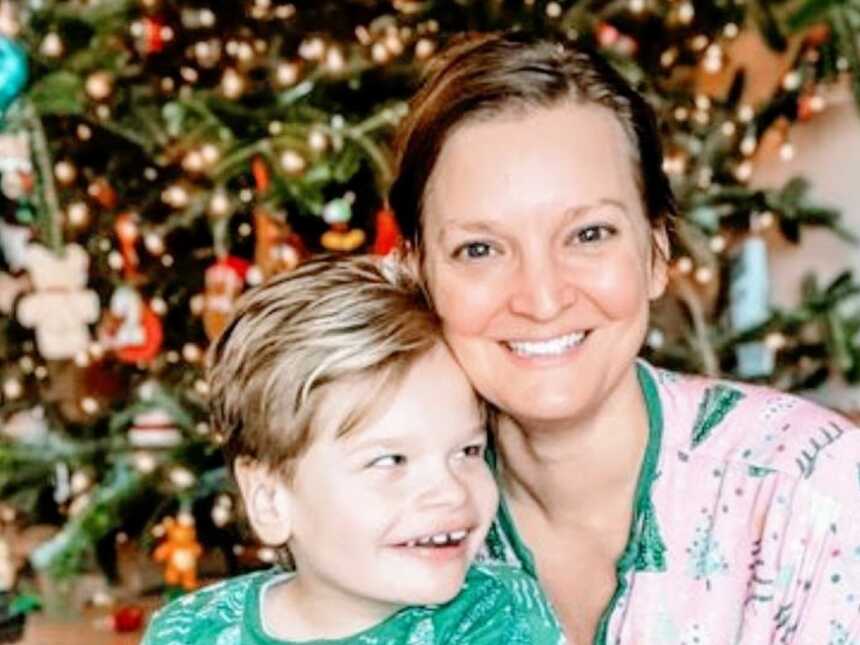 Special needs mom and son take a happy photo together in front of the Christmas tree