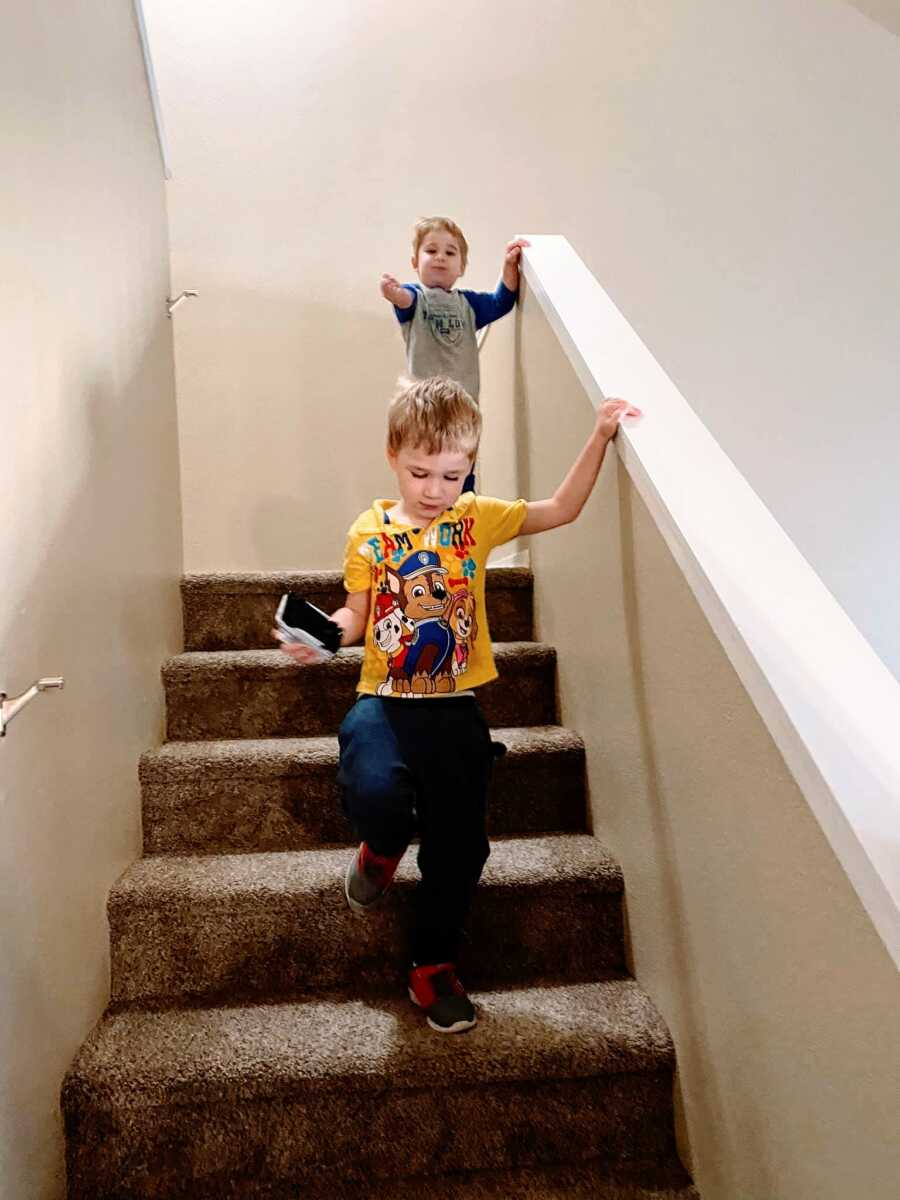 Two little boys run down the stairs together