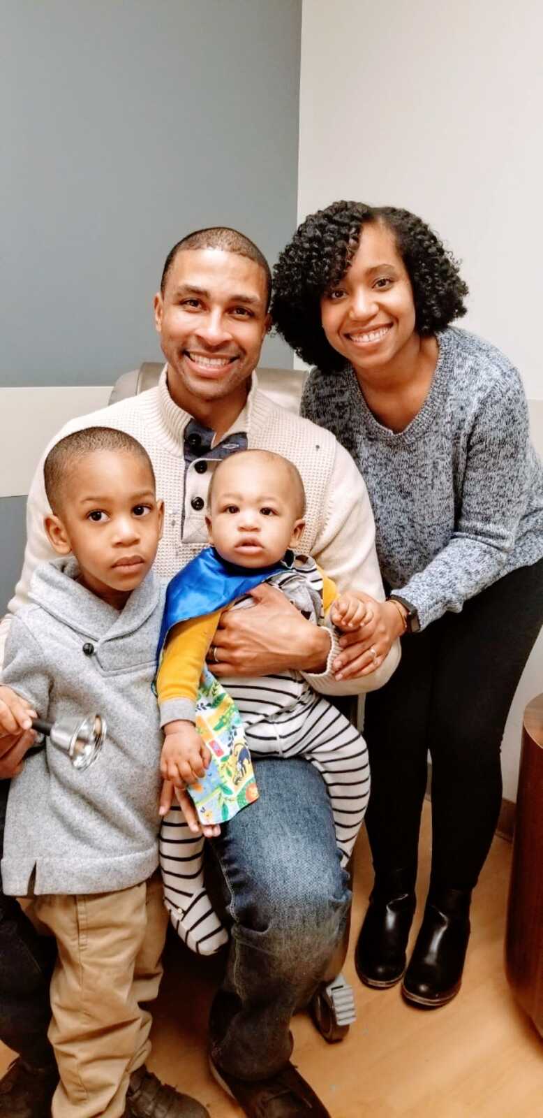 Family of four take a photo with their youngest son wearing a cape