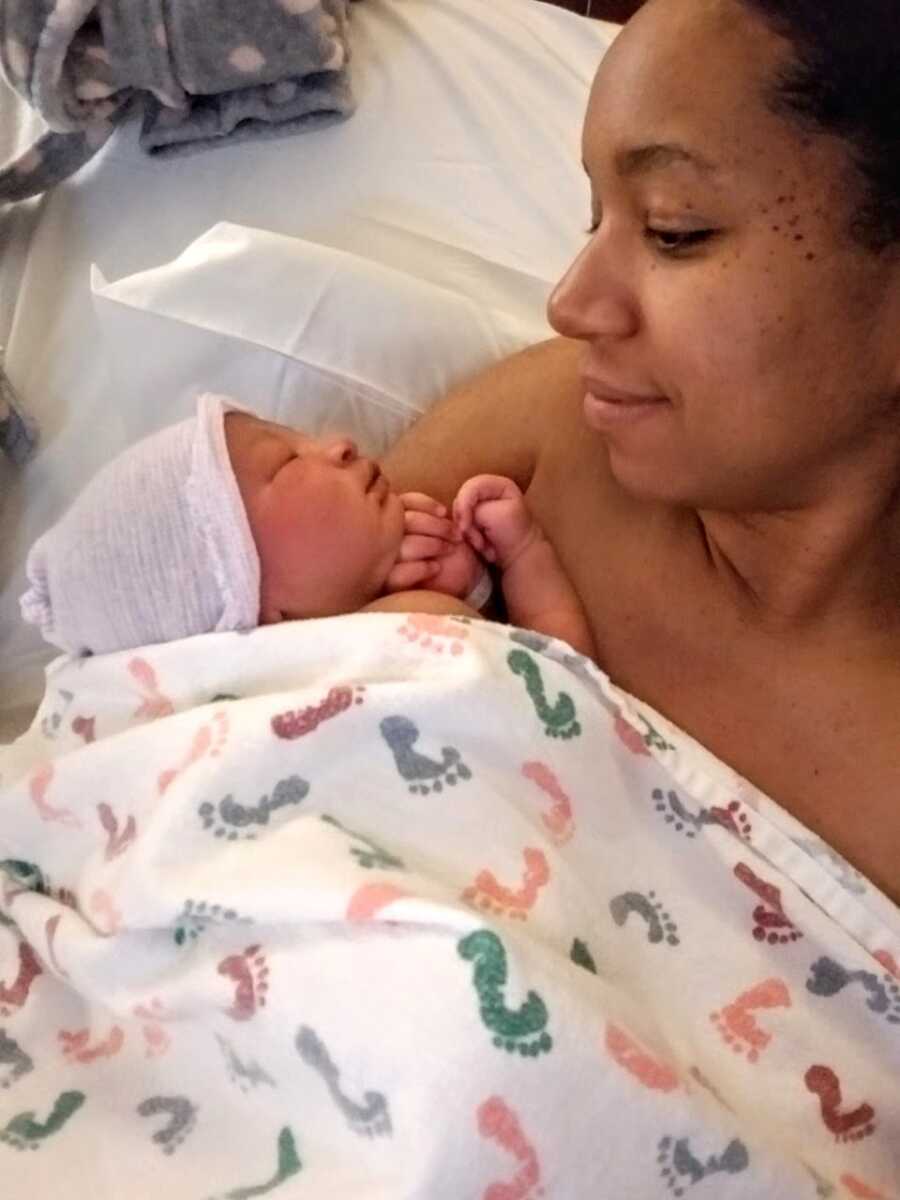 Mom looks down on newborn son while holding him after labor