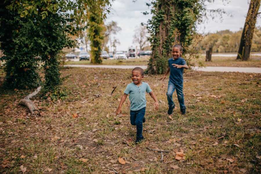 Big brother chases little brother around as they play during a photoshoot