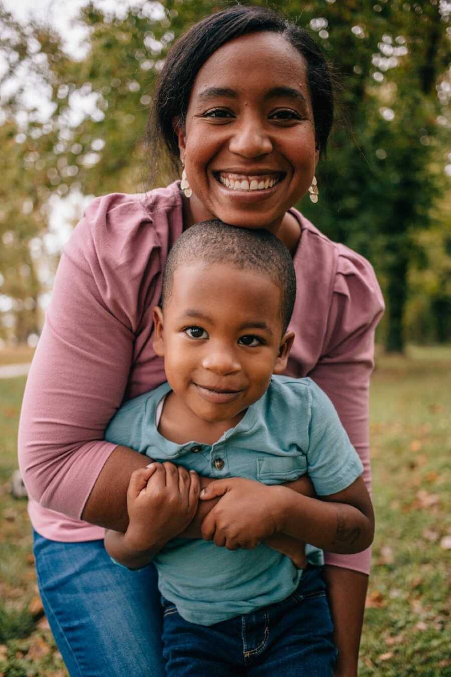 Mom smiles big while hugging her youngest son