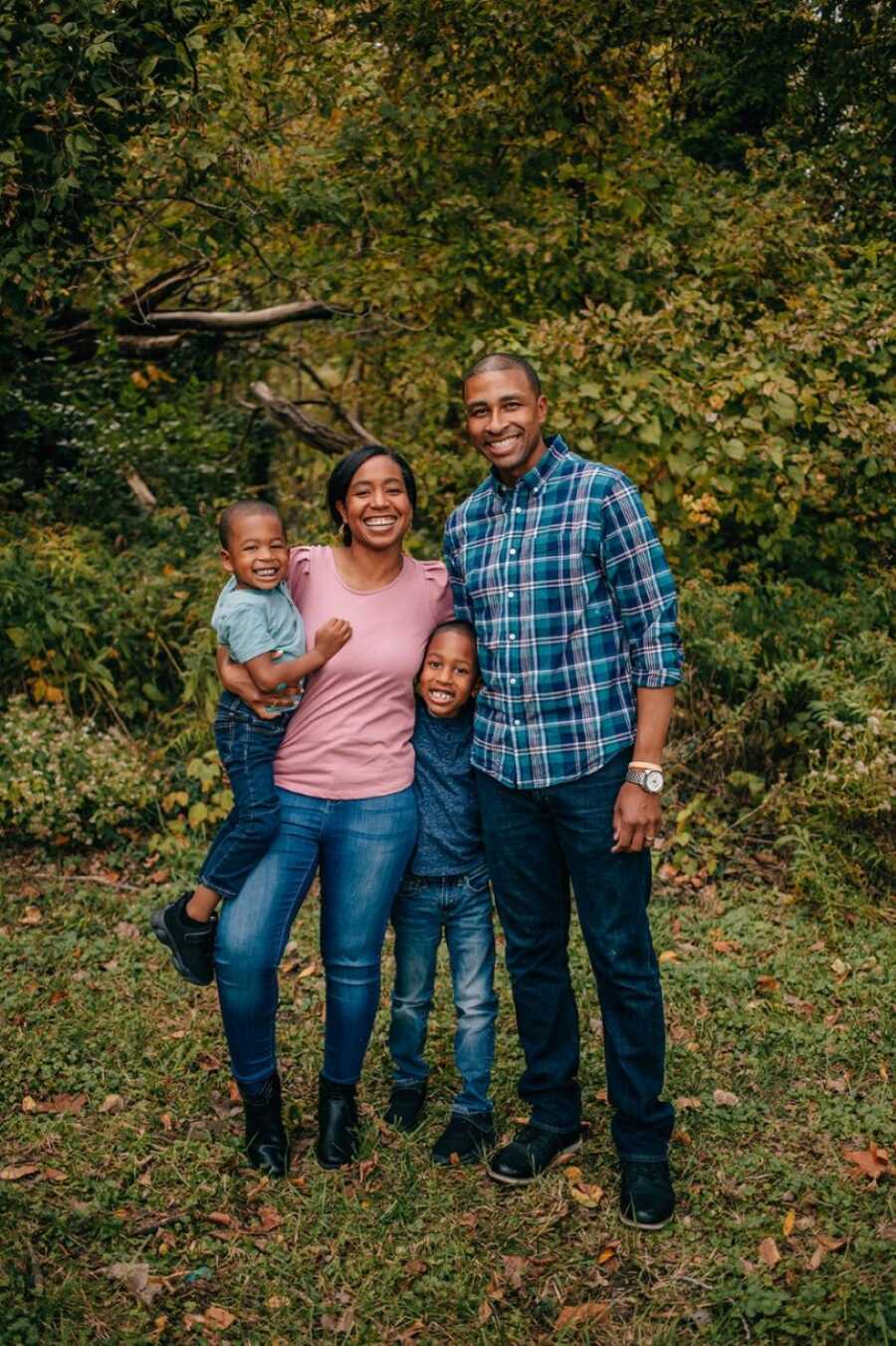 Family of four take photo with green foliage behind them