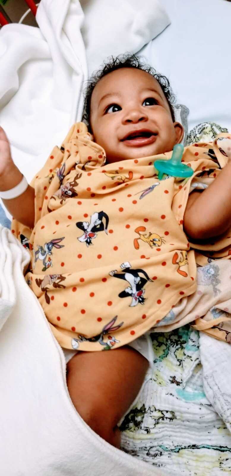 Little boy smiles while wearing Looney Tunes hospital gown