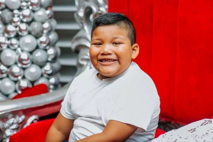 little boy sitting in santa's chair in north pole