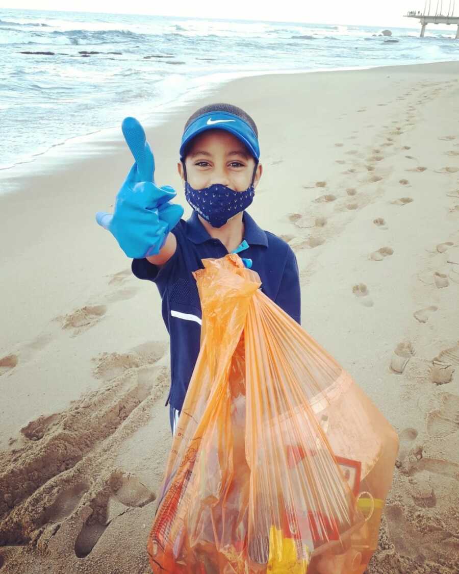 little boy cleaning up the beach to help fight climate change