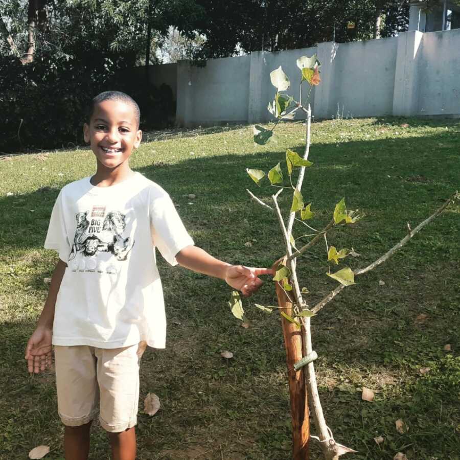 little boy with a tree that he planted with his donations