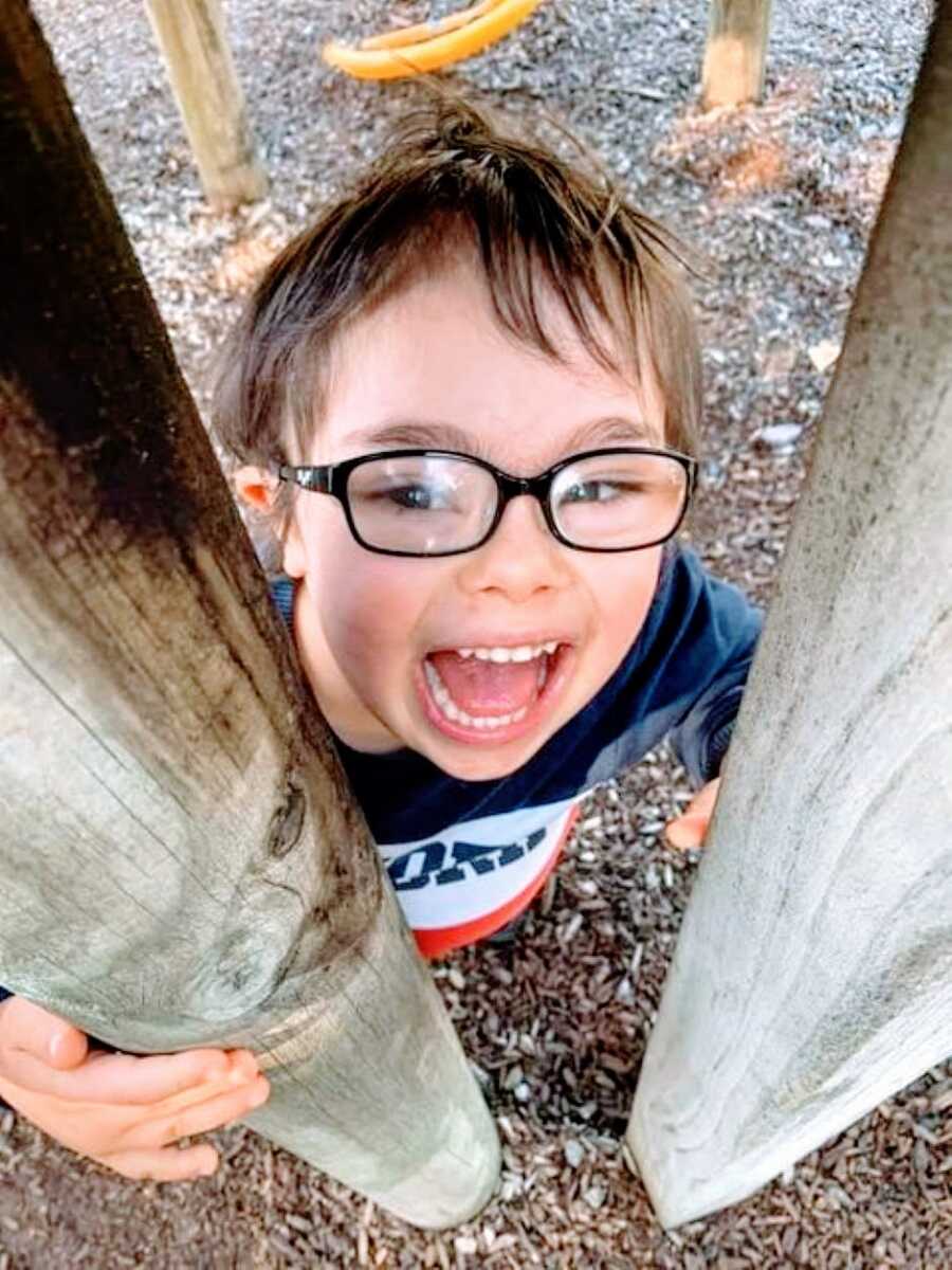 Special needs mom takes a photo of her son with down syndrome smiling and playing at the park