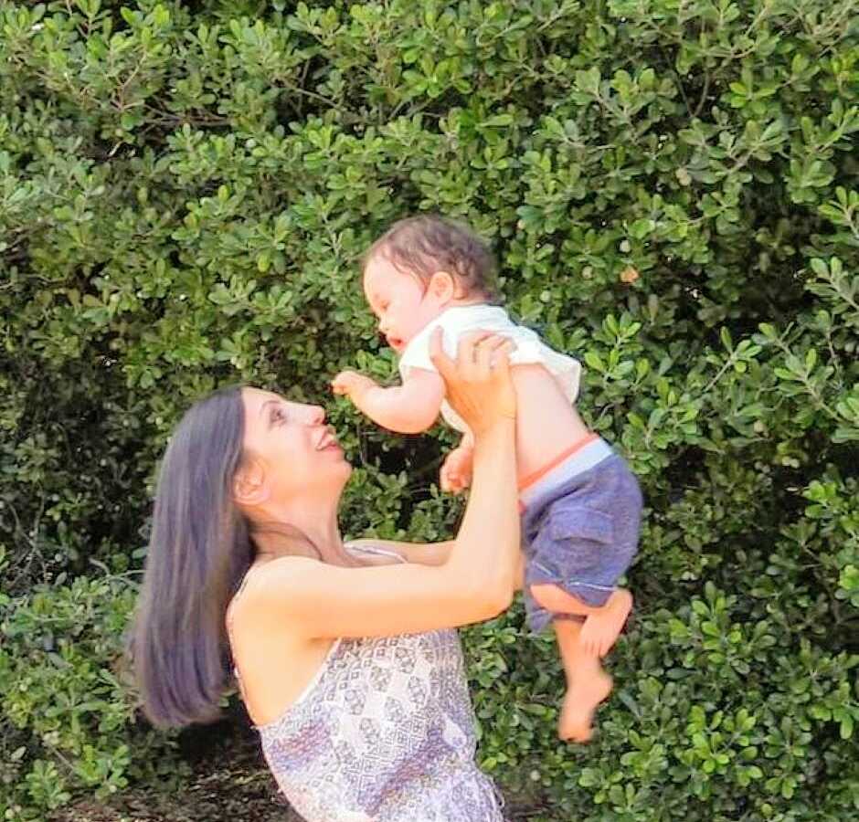 Special needs mom lifts her son with down syndrome up into the air while smiling at him