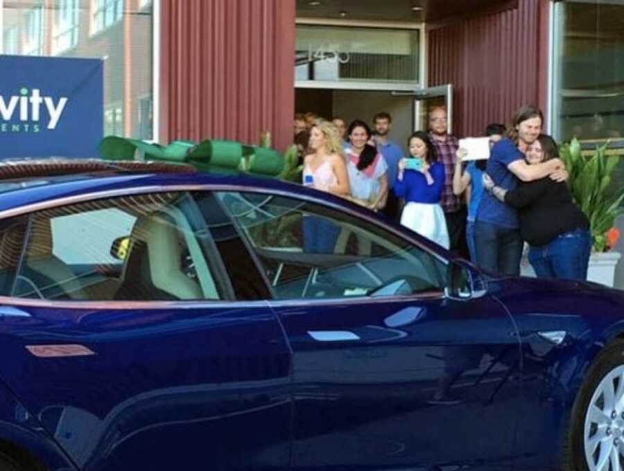 boss with his employees in front of a new car