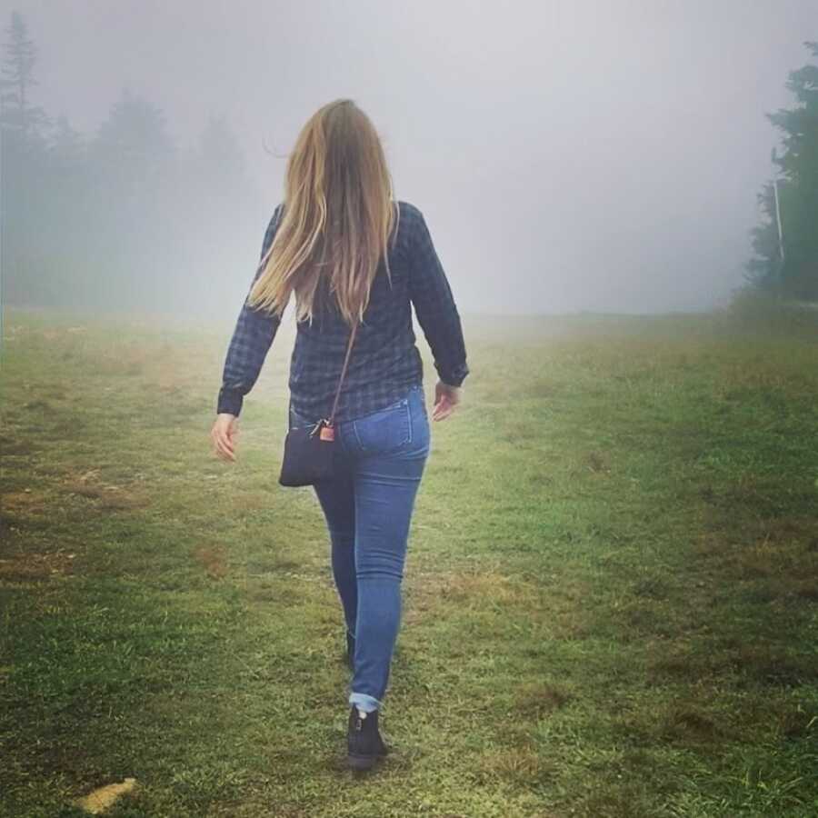 woman walking through the fog into the forest