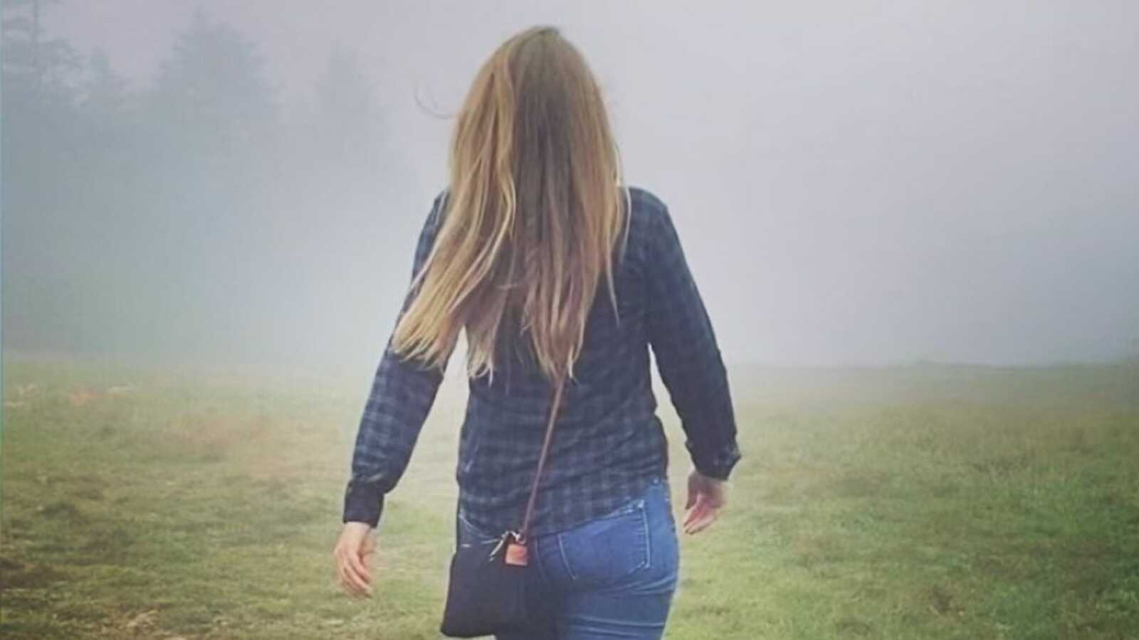 woman walking through the fog into the forrest