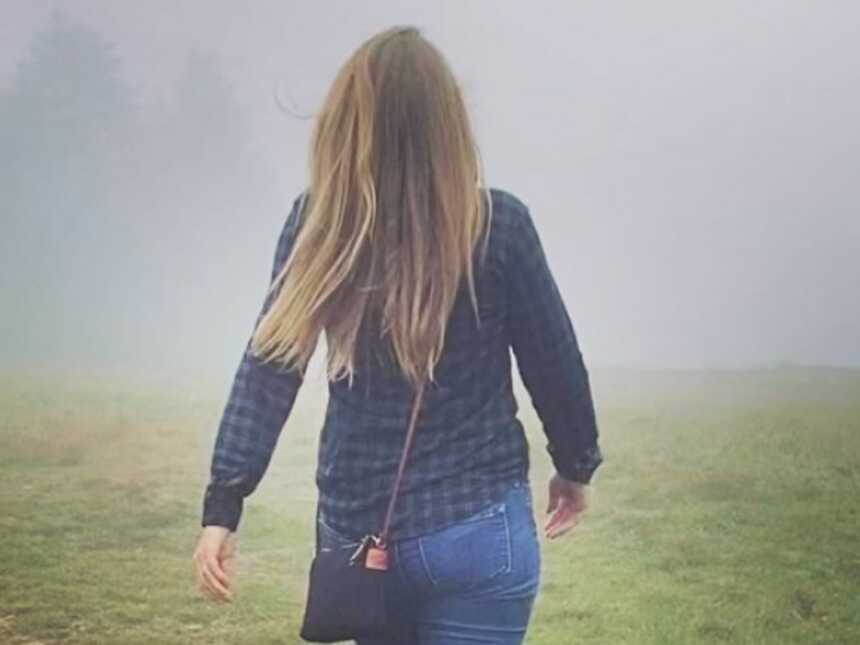 woman walking through the fog into the forrest