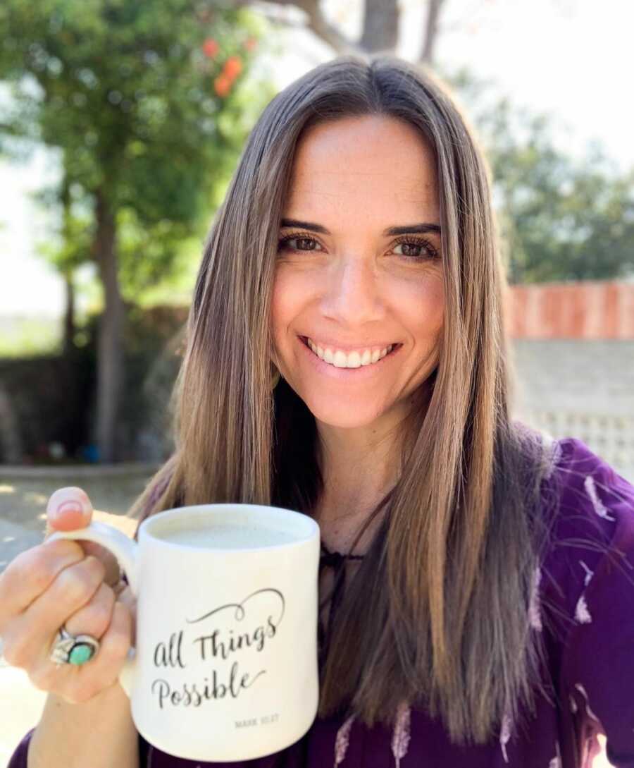 Becky holds up her coffee mug which reads, "All things possible."