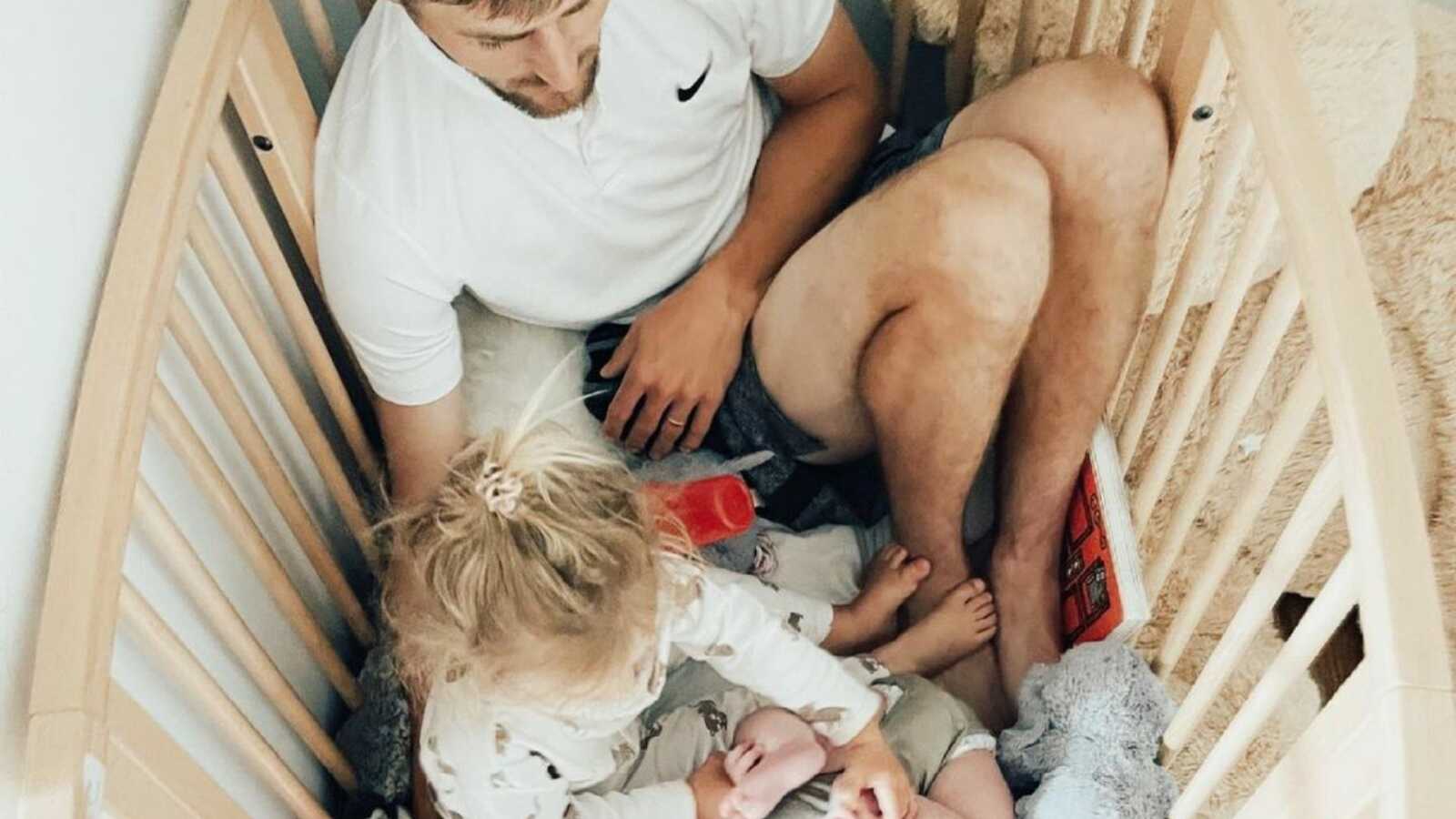 dad in the crib with his two kids