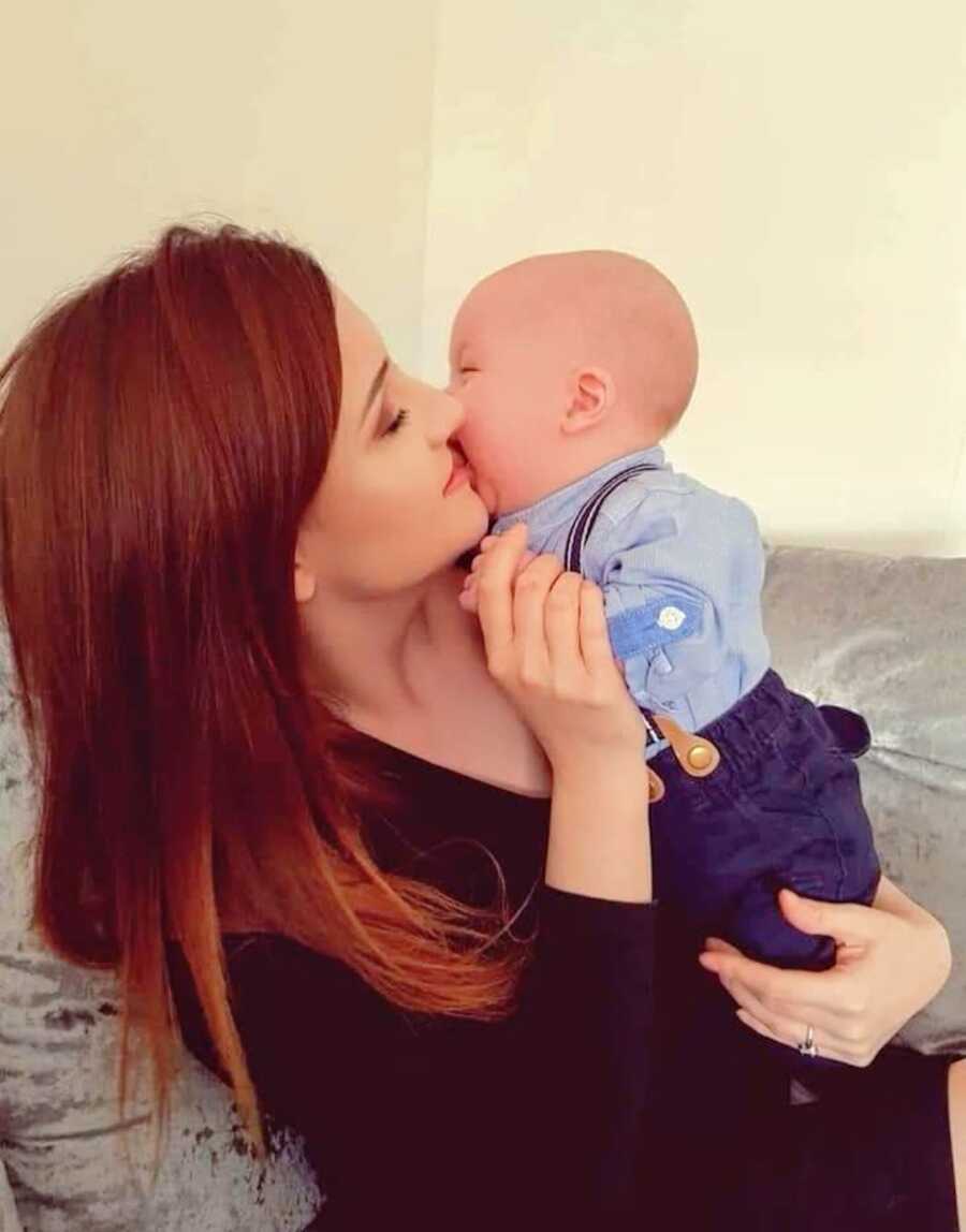 mother holds infant son as he leans into her face