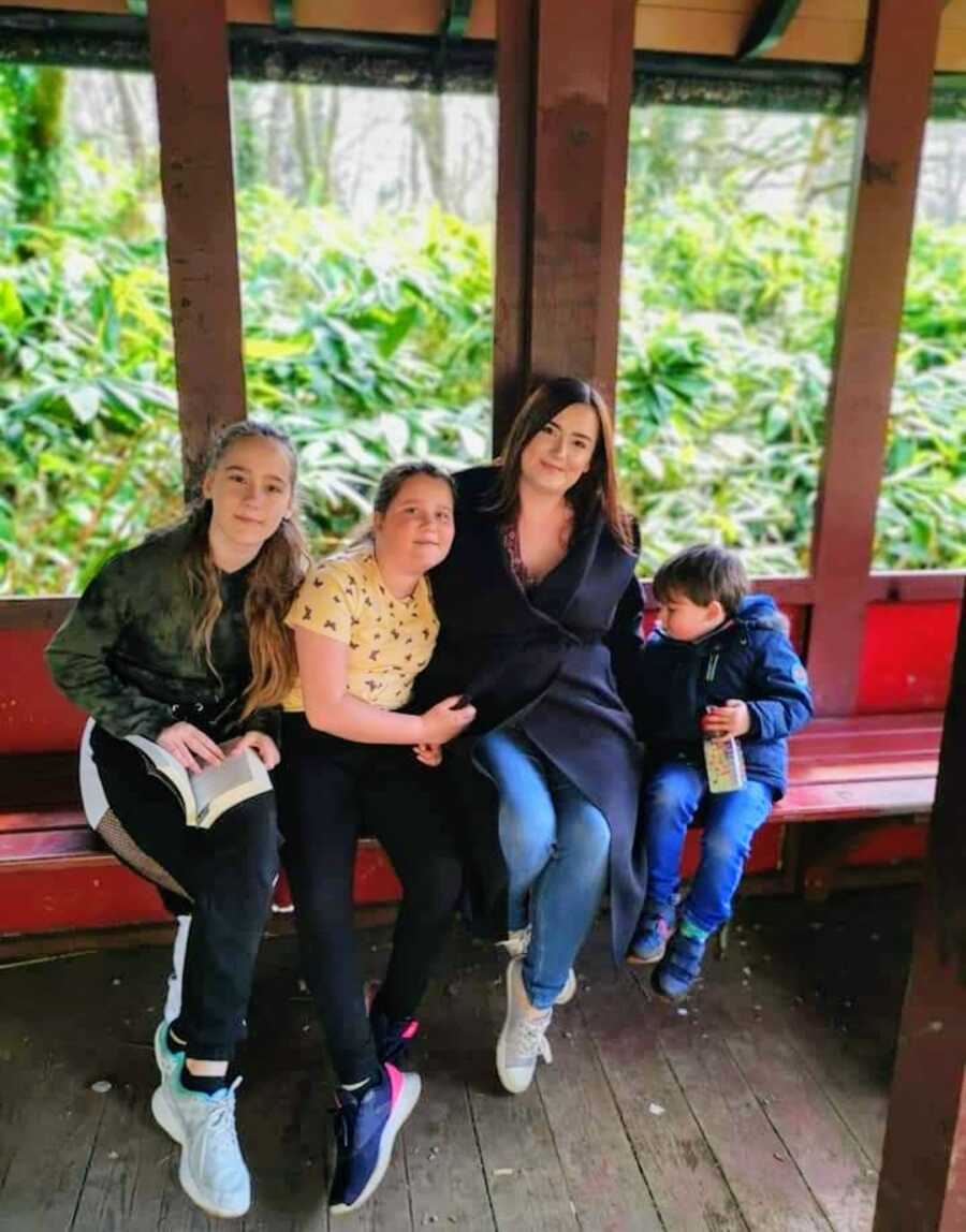 mother sitting on bench with two daughters and last born son
