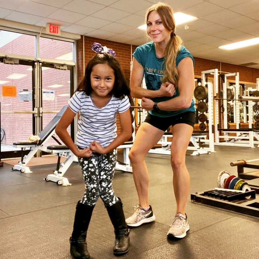 mom and little girl showing off muscles at gym