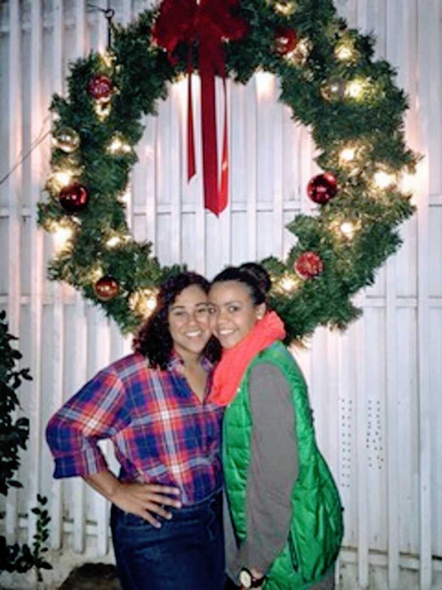 An adoptee stands with her sister by a wreath