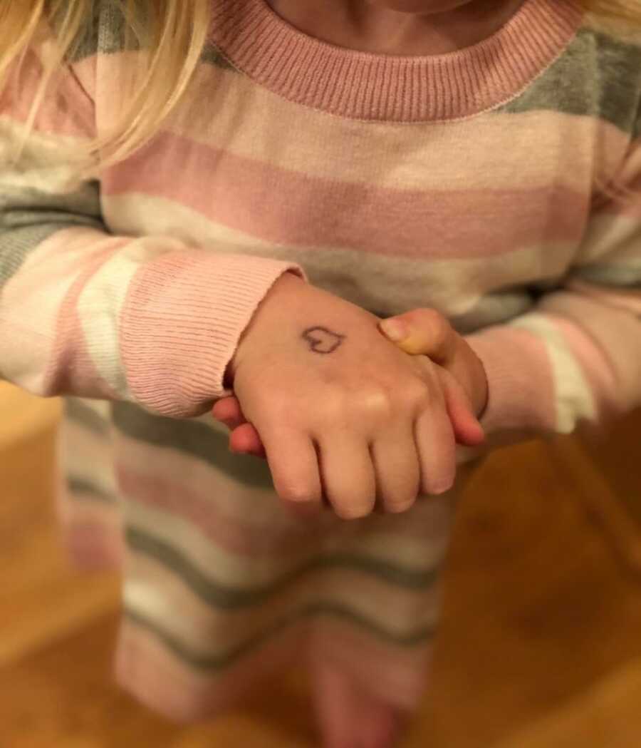 mom drawing heart on daughter's hand just in case she can't say goodbye