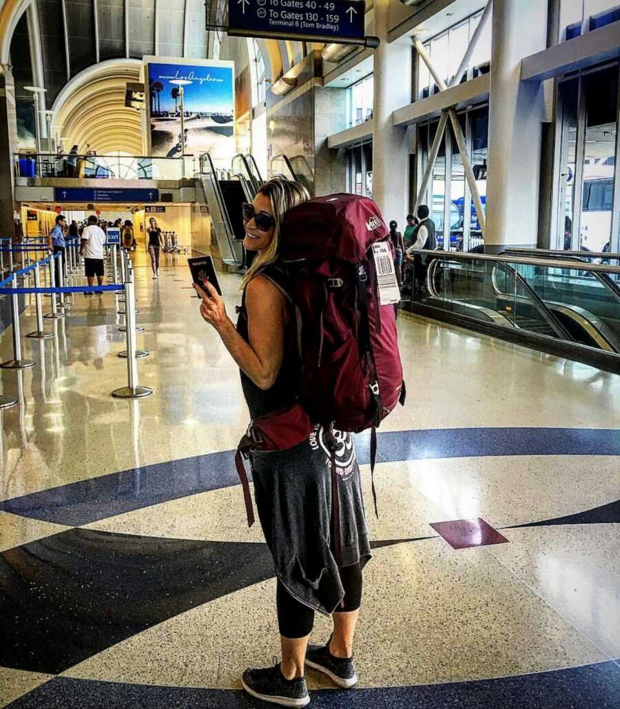 woman with her backpack in the airport with her passport ready for travel