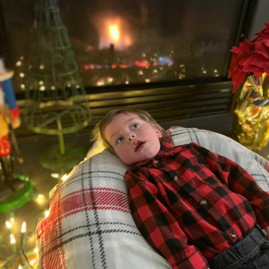 little boy laying down on a bean bag chair in front of the fire for comfort