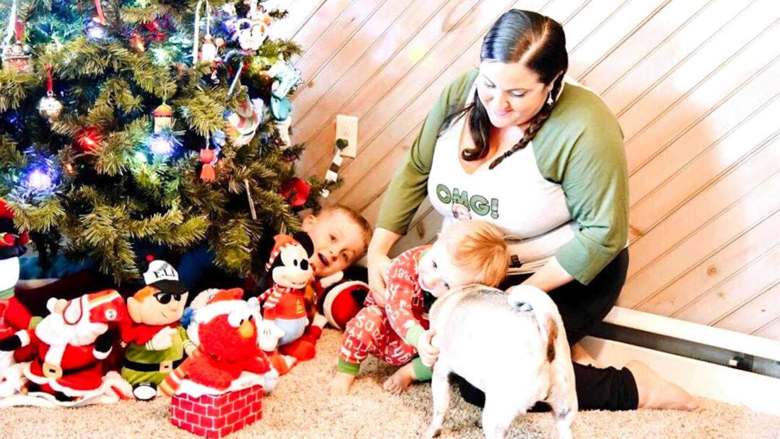 一位妈妈和孩子、小狗坐在圣诞树旁