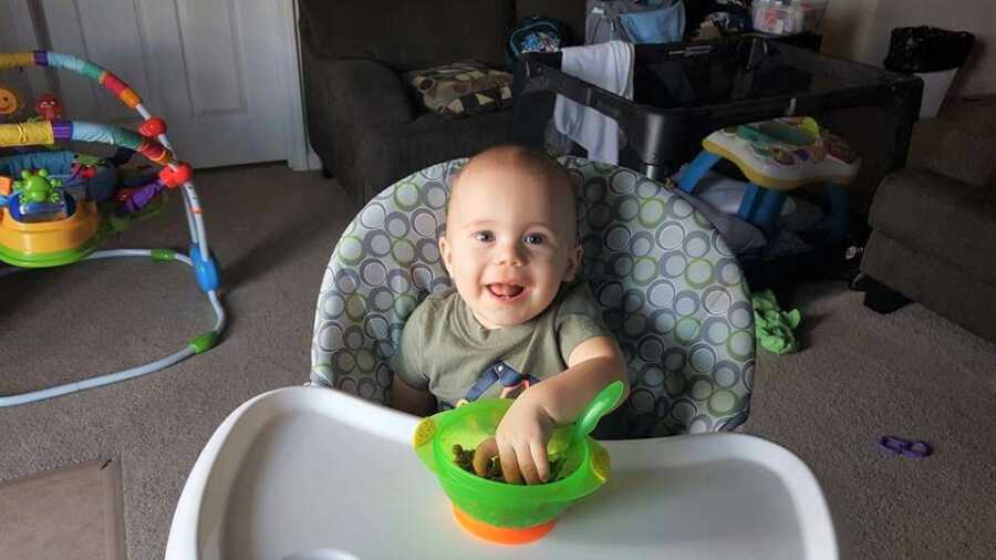 Baby with cystic fibrosis sits in his high chair eating food.