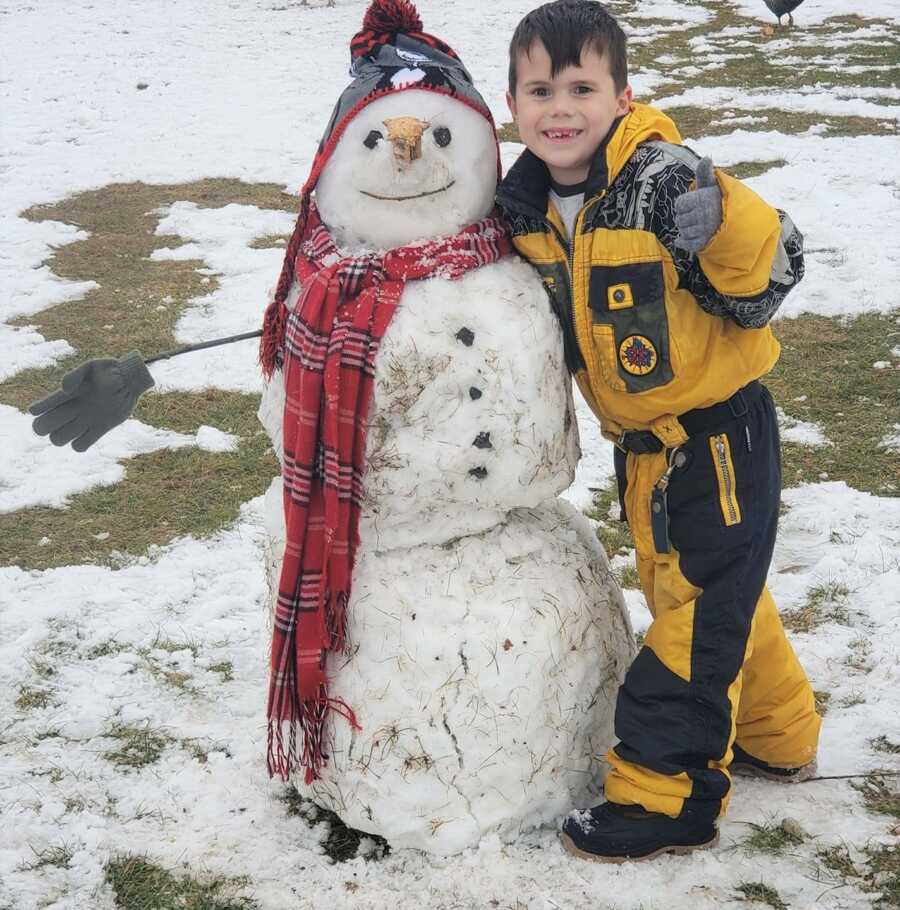 Jayden stands next to a snowman he built. 