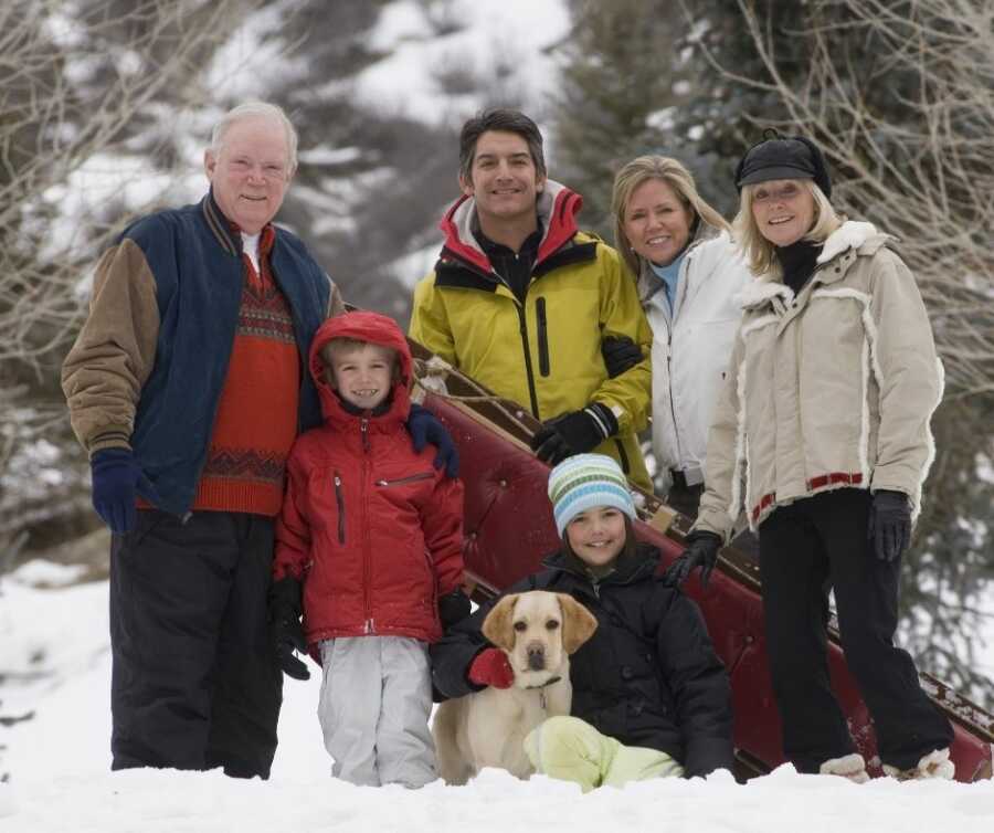 Family takes a picture while sledding with grandparents. 