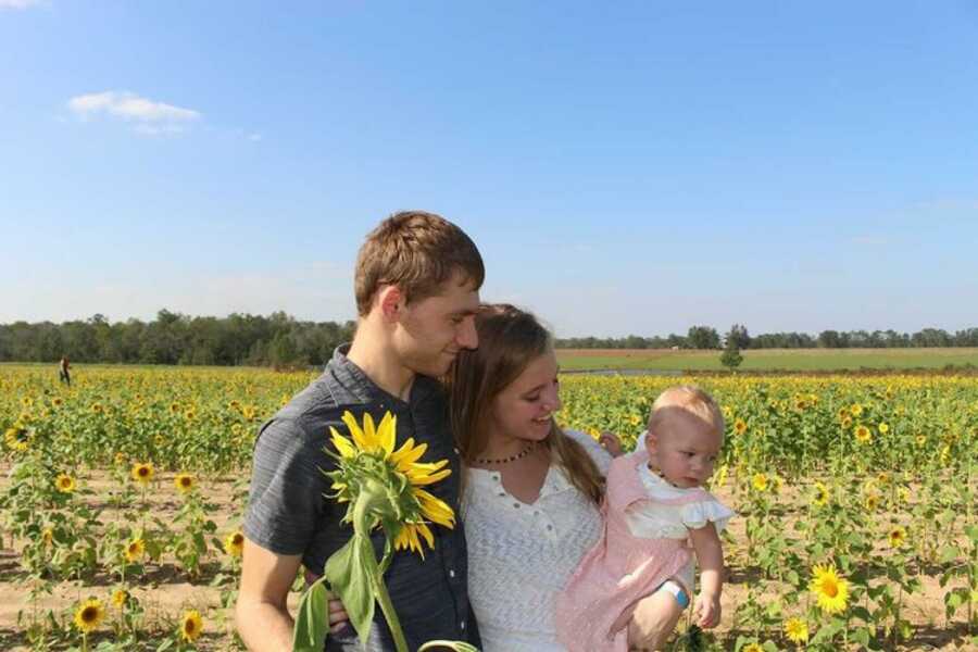 mom daughter and dad in a sunflower field