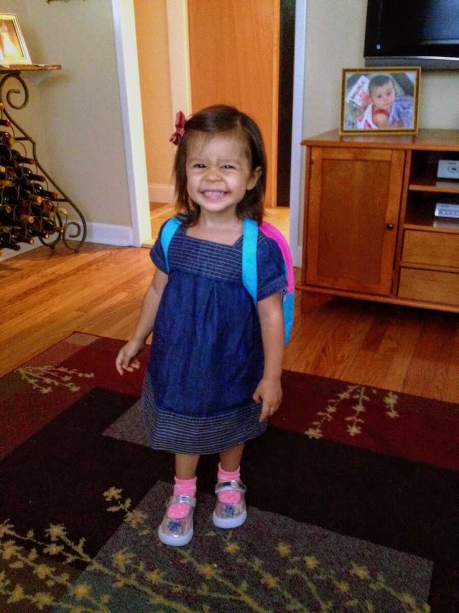 young girl poses while ready to go to school smiling with a backpack on
