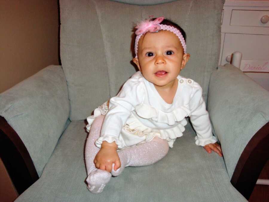 infant girl sitting on chair leaning forward