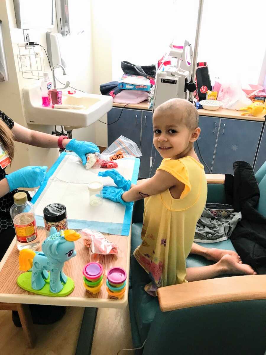 young girl with cancer in hospital receiving treatments while playing with toys
