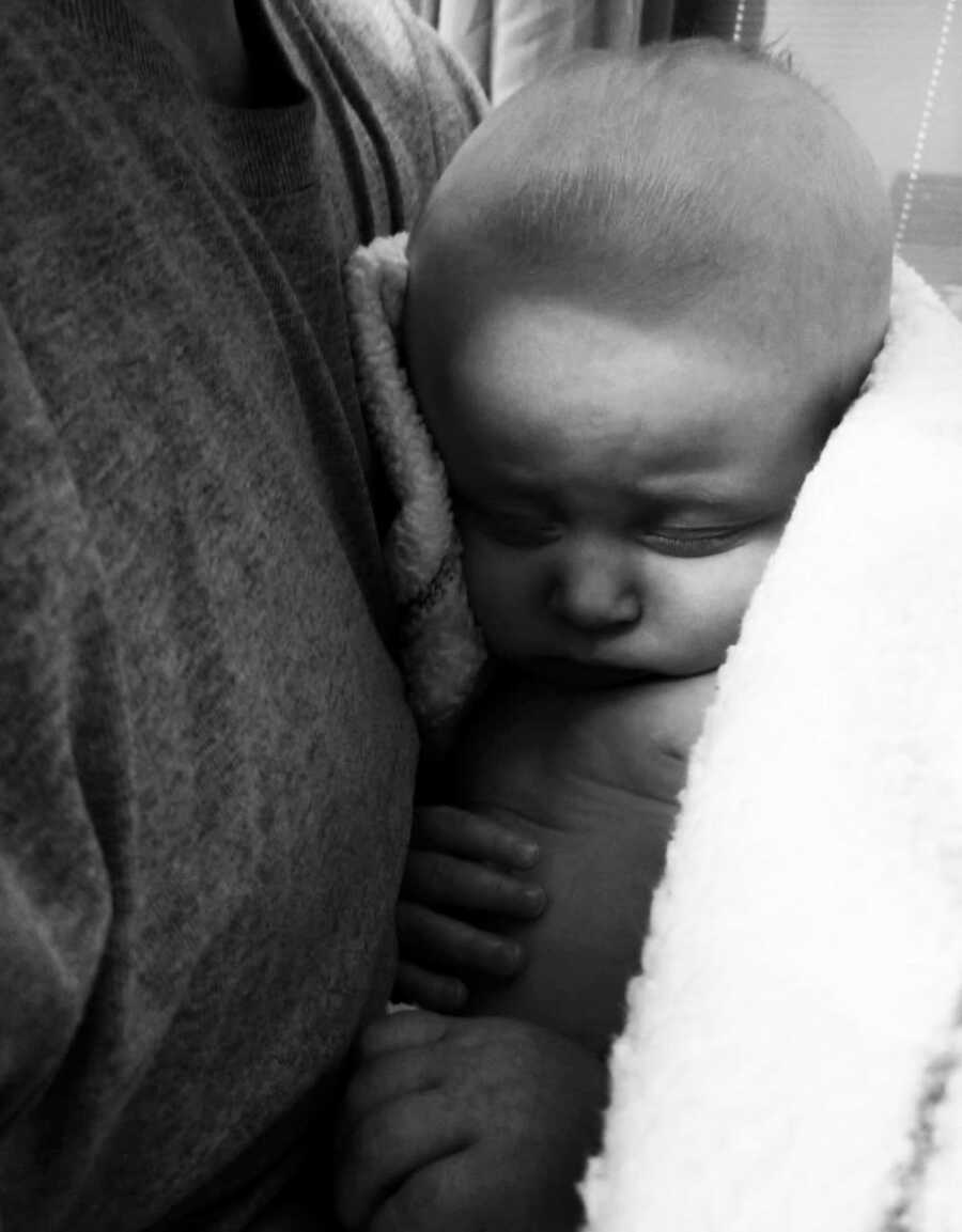 Mom holds sleeping baby against her chest. 