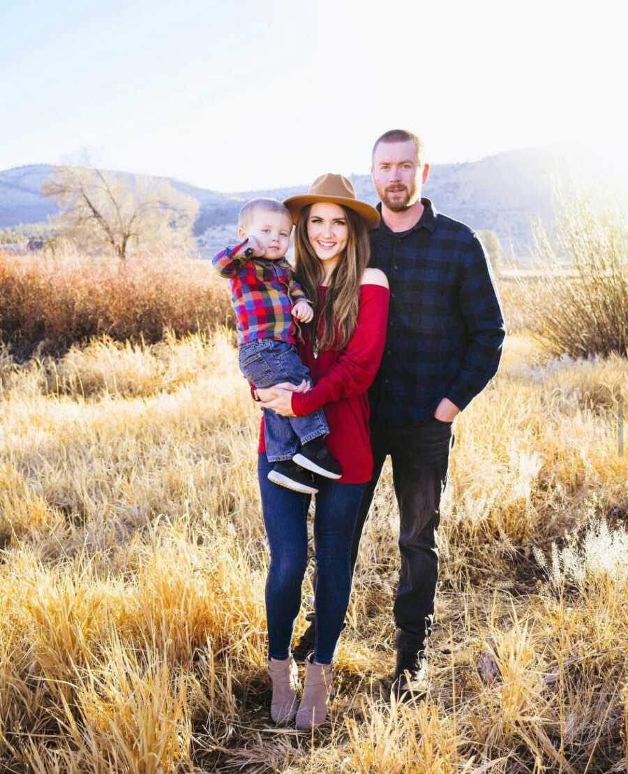 mom and dad with their son in a bare field