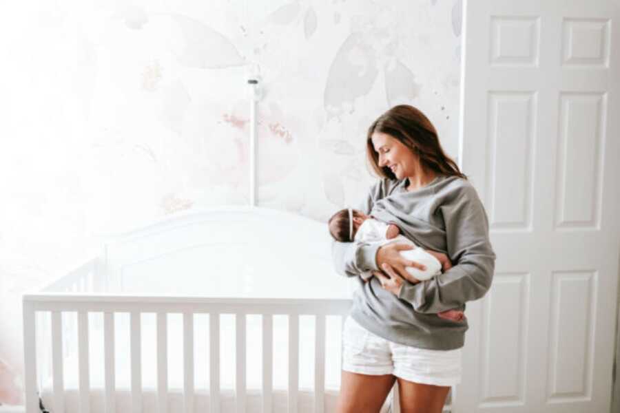 Mom holding her new born baby in her nursery