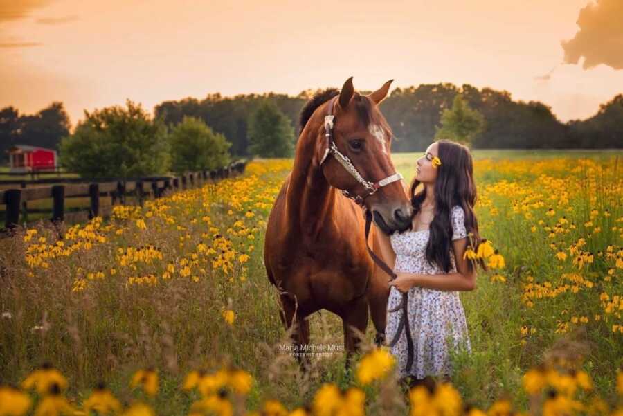 high school senior with her horse at golden hour posing for a portrait