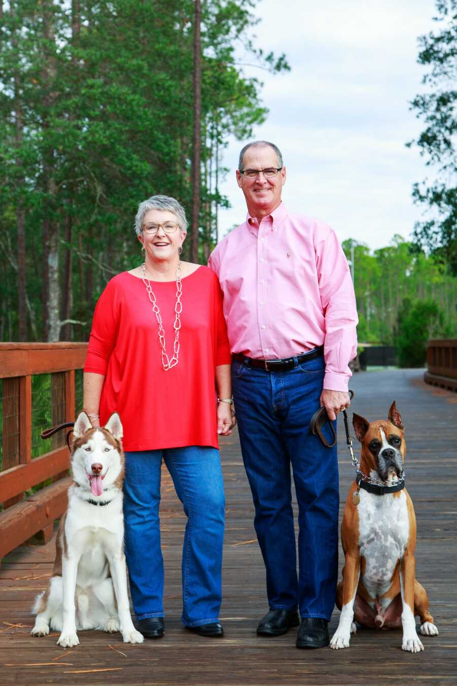 wife and husband posing for a photo with their dogs