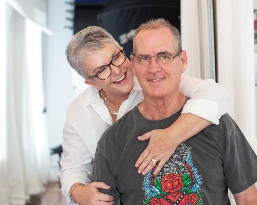 wife with her arm around her husband smiling