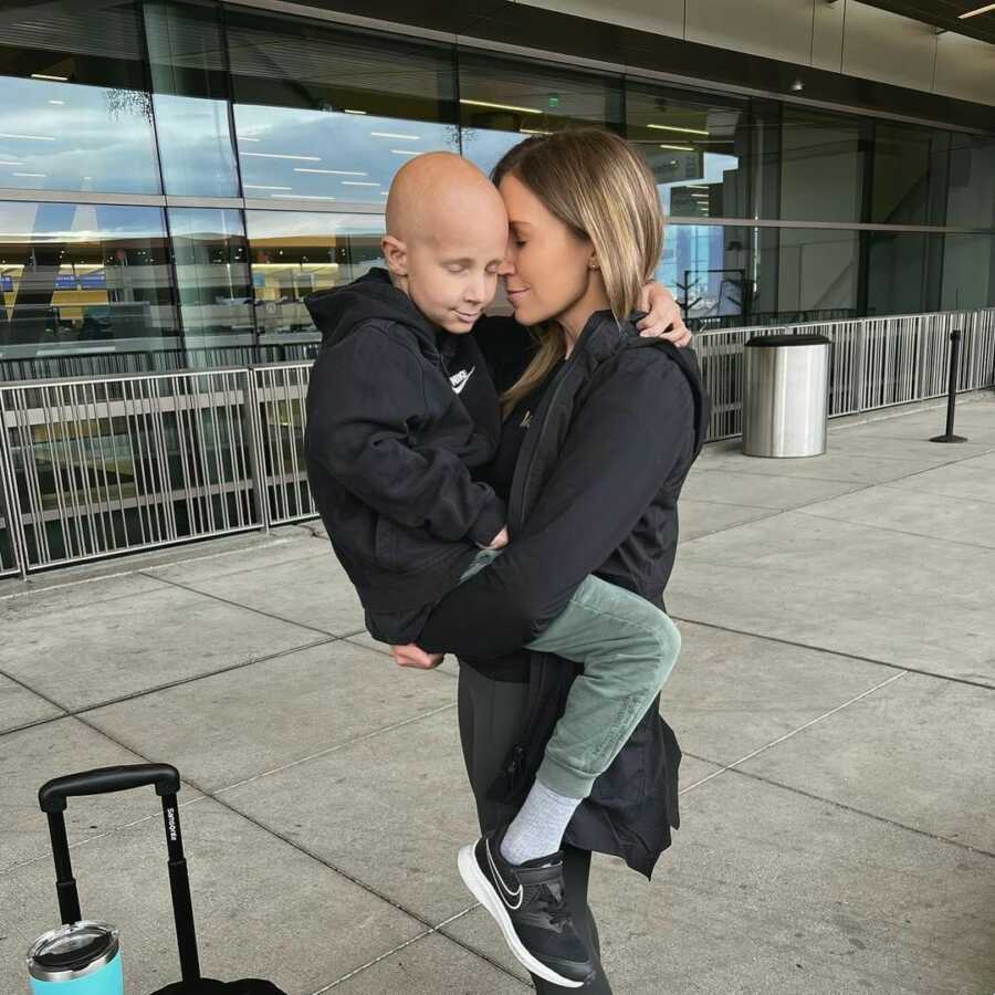 son with cancer being held by his mom while they both close their eyes